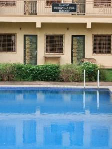 a blue swimming pool in front of a building at Kalwars Millennials Park in Karjat