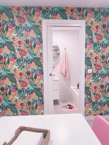 a bathroom with floral wallpaper and a mirror at Casa rosa completa-patio- BBQ-columpios-buhardilla in Campillo de Altobuey