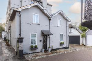 a white house with a black door on a street at River cabin & Mills Cottage in Henley on Thames