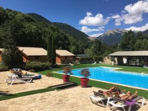 a group of people sitting in chairs near a swimming pool at CHALET MONTAGNE CLASSÉ 3 ETOILES ALPES QUEYRAs in Guillestre