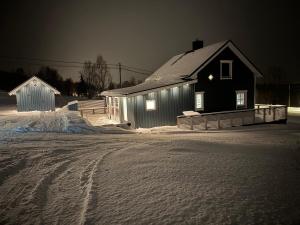 OksevikComfortable House in Lyngen的黑房子,晚上雪中