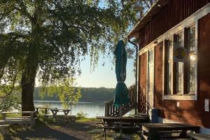 a building with tables and a umbrella next to a lake at Siaröfortet in Norra Ljustero