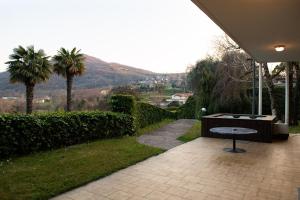 a patio with a table and palm trees and a hill at Exclusive Villa with Lake view-Private SPA in Galbiate
