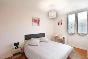 a bedroom with a large white bed with a window at Pleasant T3 near the Thermes de Marlioz in Aix-les-Bains