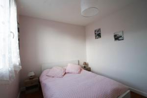 a bedroom with a bed with pink pillows on it at Pleasant T3 near the Thermes de Marlioz in Aix-les-Bains