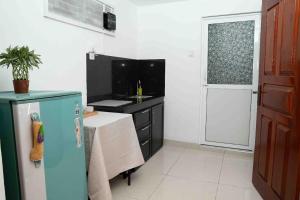 cocina con mesa, fregadero y nevera en Serendib Hideout, en Negombo