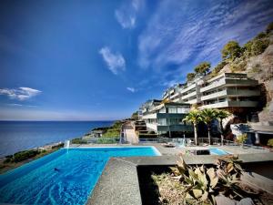 a swimming pool in front of a building next to the ocean at Sunny Home Costa Plana-Monaco -Cap D'Ail in Cap d'Ail
