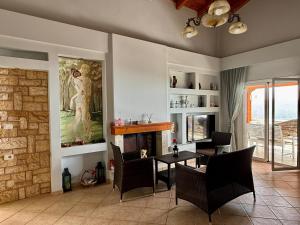 a living room with a fireplace and a table and chairs at Villa Nefeli in Piqeras