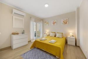 a white bedroom with a yellow bed and two night stands at Casa Azul in Portimão