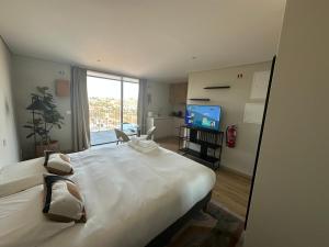 a bedroom with a large white bed and a television at New Douro 908 with pool shared and parking in Vila Nova de Gaia