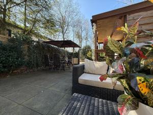 a patio with a couch and a table and chairs at VELUWE CHALET HOENDERLOO Private Jacuzzi, Park Swimming Pool and Children's Entertainment in Hoenderloo