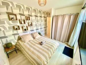 a bedroom with a bed with a striped bedspread and a wall at Le Prestige Terrasse-Cocon familial cosy, Billard & Jacuzzi avec vue sur Paris in Le Blanc-Mesnil