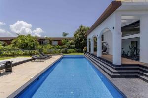 a swimming pool in the backyard of a house at Mini Paradise Apartment by tisyastays in Candolim