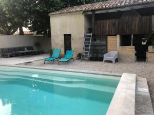 a house with two chairs and a swimming pool at Mas de la Guillaumone in Arles