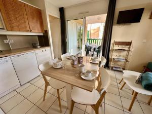 a kitchen with a wooden table and white chairs at nid douillet au milieu des pins entre lac et océan in Carcans