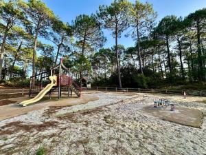 a playground with a slide in a park at nid douillet au milieu des pins entre lac et océan in Carcans