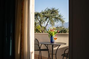 un tavolo con un bicchiere di vino e fiori su un balcone di Hotel Maiuri Pompei a Pompei