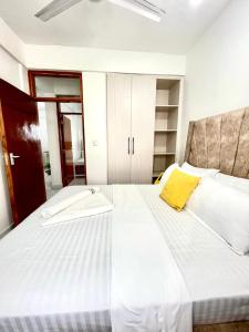 a bedroom with a large white bed with a yellow pillow at Homely Hideaway Buxton Point Mombasa in Mombasa +8 photos