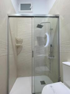 una ducha con puerta de cristal en un baño en Cerca del centro y luminoso, en Madrid