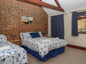 ein Schlafzimmer mit zwei Betten und einer Ziegelwand in der Unterkunft Daisy Cottage in Bridport