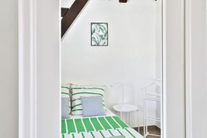 a bedroom with a bed with green and white pillows at L'évasion, terrasse parking in Zillisheim