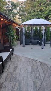 a patio with an umbrella and benches and plants at Къща за гости Иванови in Targovishte