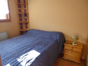 a bedroom with a blue bed and a night stand at Appartement Morillon 500m ski et randonnée in Morillon