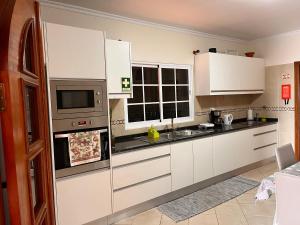 a kitchen with white cabinets and a microwave at Apartamento Pestana in Arco da Calheta