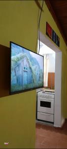 a tv on a wall with a painting of a house at Hospedaje Los Buenos Aires in Santa Ana