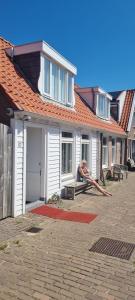 a man sitting on a bench in front of a house at Viking in Egmond aan Zee
