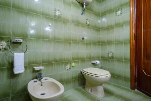 a green tiled bathroom with a toilet and a sink at Alla Rosa Dei Venti - North Wind House in Torre Specchia Ruggeri +17 photos