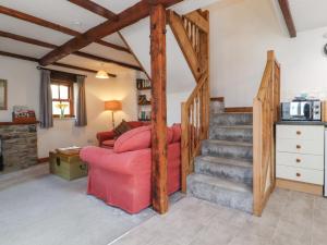 a living room with a red couch and stairs at Mallards Nest in Skipton