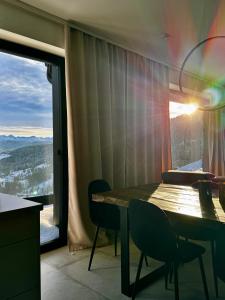 a dining room with a table and a large window at Bacówki Resort in Ochotnica Górna