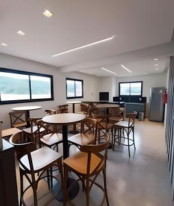 a dining room with tables and chairs and windows at Apto com Piscina / até 3 pessoas in Limeiro