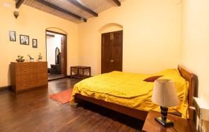 a bedroom with a bed and a dresser and a lamp at Shanthiniketan Heritage in Coonoor