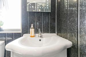 a white bathroom sink with a soap bottle on it at Cozy 3 Bedroom House For Short and Long Stay in Lower Gornal +16 photos