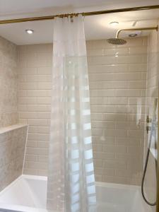 a shower with a white shower curtain in a bathroom at Home in Upminster in Upminster