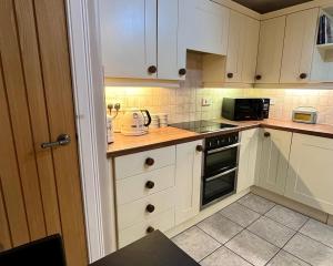 a kitchen with white cabinets and a stove top oven at Beach Cottage in a Tranquil Location in Kingsbarns