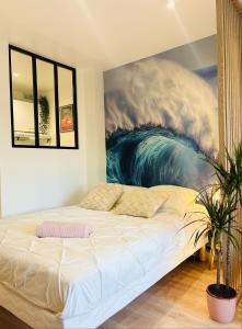 a bed in a room with a painting on the wall at DUNE Océan Luxe Appartement, Accès Plage privé, Parking & Wifi 50m Océan Surf in Seignosse