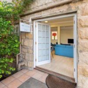 Una puerta abierta de un edificio de piedra con patio. en Queen's Residences by BON Hotels, en Oudtshoorn