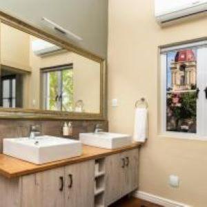 un baño con lavabo y espejo en Queen's Residences by BON Hotels, en Oudtshoorn 14 fotos más