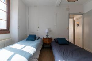 two beds in a room with a mirror at Maison Cosy - Coeur de Village - Cour Privative in Bagnères-de-Bigorre