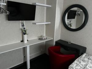 a hotel room with a tv and a red chair at Chambre Mawa Tout Confort in Vaulx-en-Velin