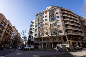 Un edificio alto en una calle de la ciudad con coches aparcados delante. en Stay U-nique Apartment Rossello II, en Barcelona