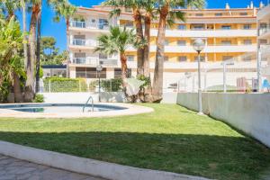 a building with palm trees and a pool in the grass at Apartment El Sol in Moraira