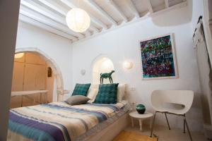 a small bedroom with a bed and a chair at La Maison Blanche -Les Houchs De Djerba in Erriadh