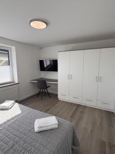 a white bedroom with a bed and a desk at Ferien auf dem Land nahe der Ostsee in Hasselberg