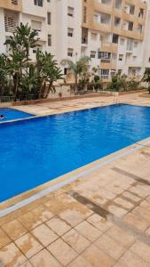a large blue swimming pool in front of a building at Private room in a shared apartment with pool in Agadir