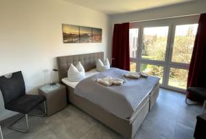 1 dormitorio con 1 cama con silla y ventana en Apartment Seerose, Am Alten Deich 14, Haus 2 Whg. 6 (Parkplatz 27), en Dangast