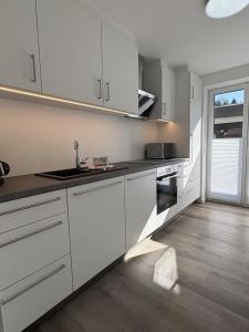 a white kitchen with a sink and a stove at Ferien auf dem Land nahe der Ostsee in Hasselberg